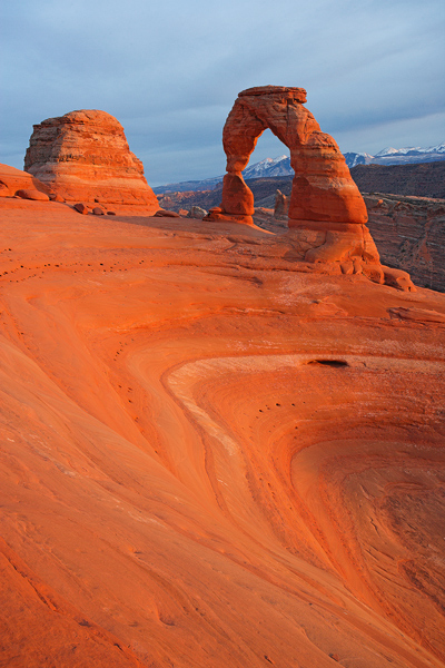 Delicate Arch, in Arches National Park, bathed in the warm light of sunset on a frigid Christmas day. The La Sal Mountains can...